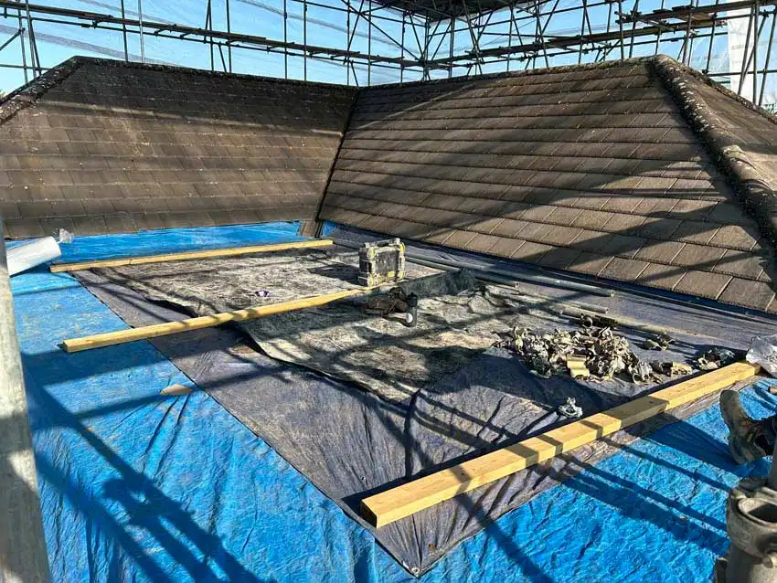 LJT Construction re-roofing job: roof stripped back under scaffolding and a protective sheet