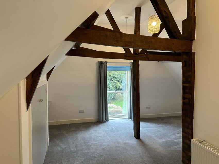 LJT Construction barn conversion: finished room with exposed oak trusses and garden doors