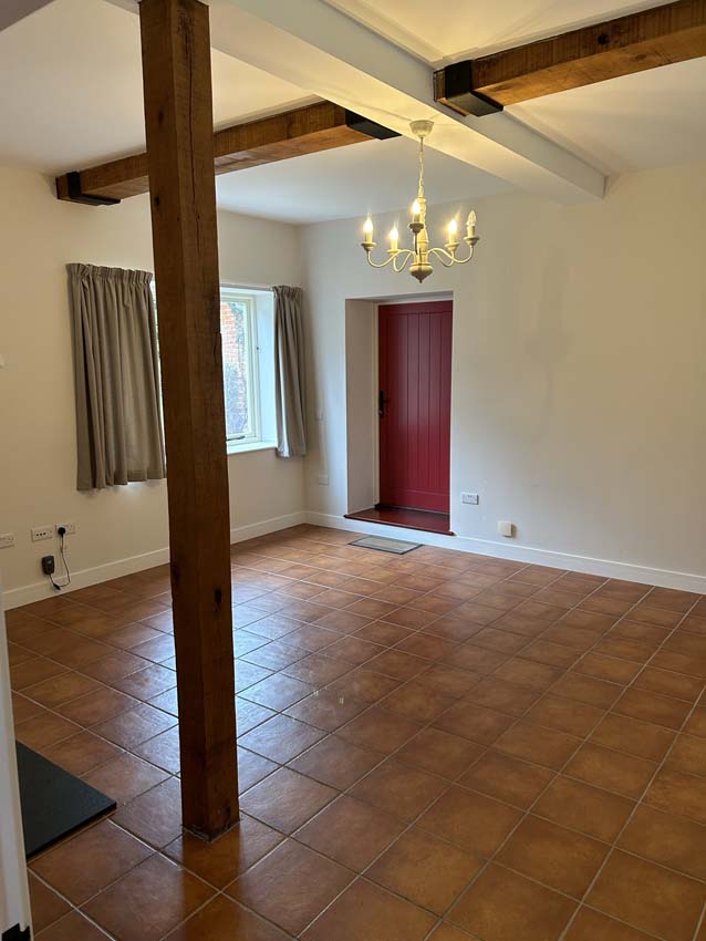 Tiled room with an oak post, beams and a red door