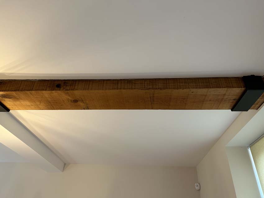 Original oak beam across a white plastered ceiling